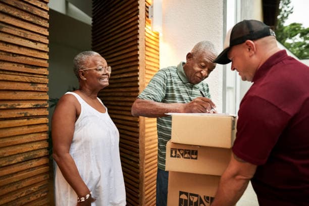 An older woman at her front door taking in a delivery of parcels