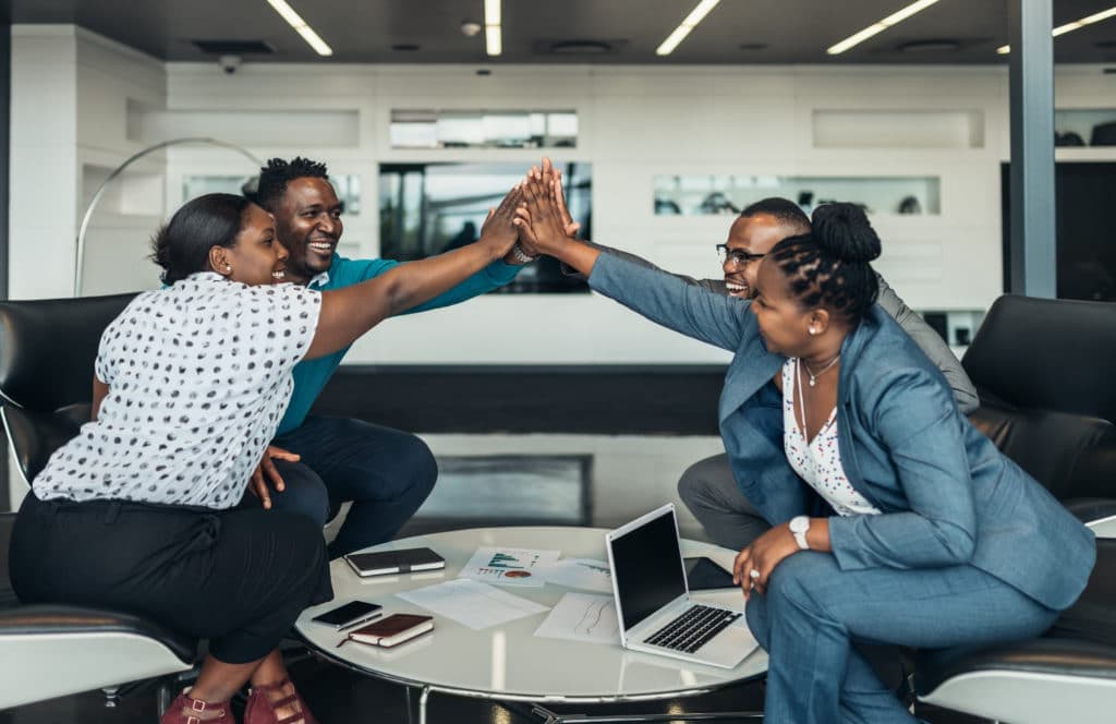 Consultancy team high-fiving across a meeting table after a successful session
